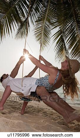 Couple playing on swing at beach View Large Photo Image Stock Photograph - Couple playing on swing at beach. Fotosearch
