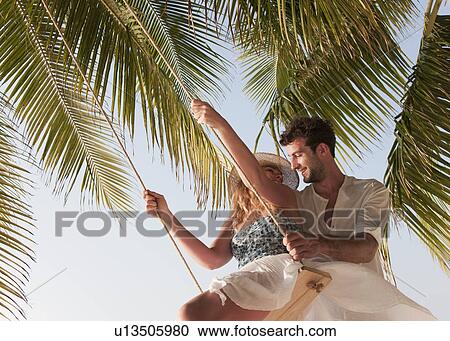 Stock Image - Couple playing on swing. Fotosearch
