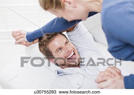 Couple playing together on couch View Large Photo Image Stock Image - Couple playing together on couch. Fotosearch