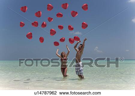 Stock Image - Couple playing with balloons on beach. Fotosearch