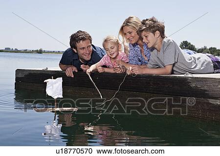 Stock Image - Couple playing with toy boat on dock. Fotosearch
