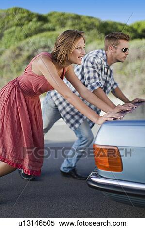 Couple pushing broken down car View Large Photo Image Stock Photography - Couple pushing broken down car. Fotosearch