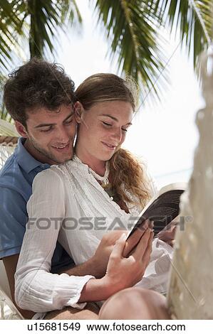 Stock Photo - Couple reading in hammock on beach. Fotosearch