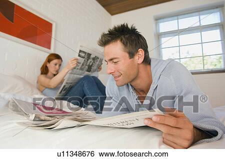 Stock Photograph - Couple reading newspaper in bed. Fotosearch