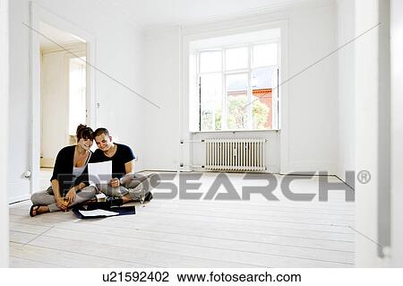 Stock Image - Couple reading papers in new home. Fotosearch