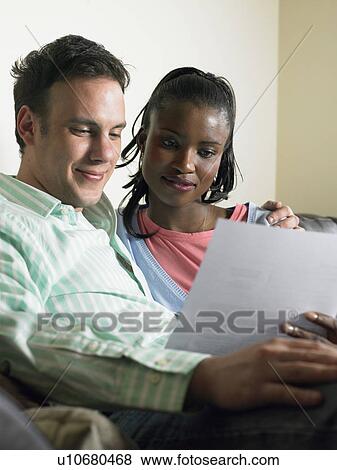 Couple reading together on couch View Large Photo Image Stock Photo - Couple reading together on couch. Fotosearch