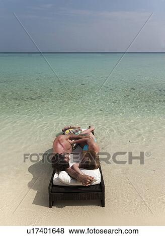 Couple relaxing on daybed at beach View Large Photo Image Stock Photo - Couple relaxing on daybed at beach. Fotosearch