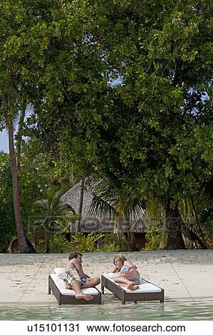 Couple relaxing on daybeds at beach View Large Photo Image Stock Image - Couple relaxing on daybeds at beach. Fotosearch