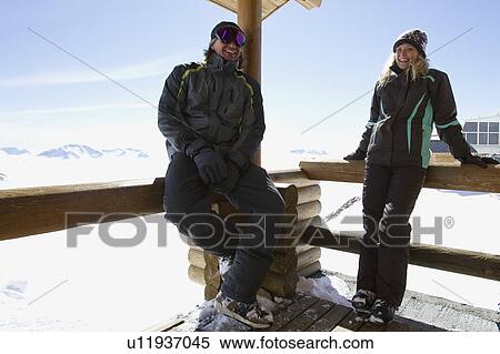 Stock Photography - Couple relaxing on ski lodge balcony. Fotosearch