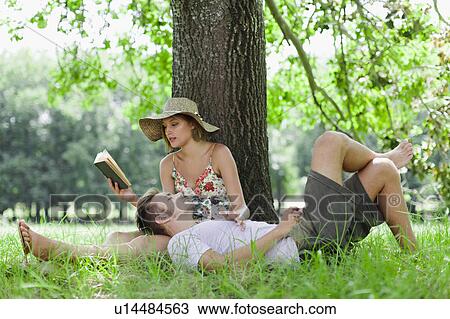 Stock Image - Couple relaxing under tree together. Fotosearch