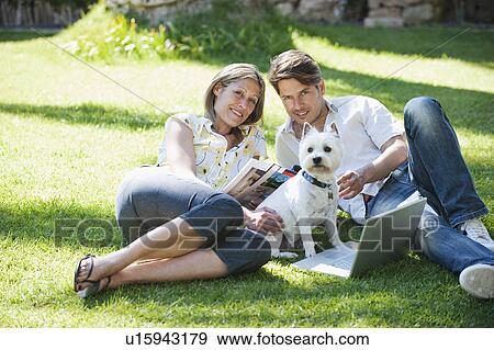 Couple relaxing with dog in grass View Large Photo Image Stock Photo - Couple relaxing with dog in grass. Fotosearch