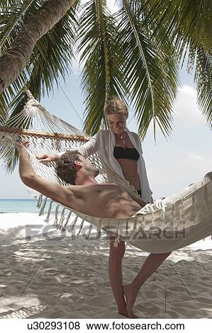 Stock Photo - Couple relaxing with hammock on beach. Fotosearch
