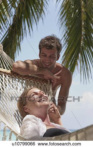 Couple relaxing with hammock on beach View Large Photo Image Stock Photograph - Couple relaxing with hammock on beach. Fotosearch