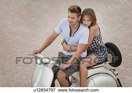 Stock Photo - Couple riding scooter together. Fotosearch