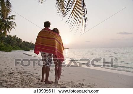 Stock Image - Couple sharing towel on tropical beach. Fotosearch