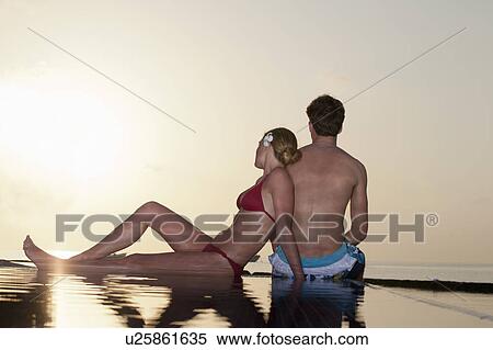 Couple sitting at edge of infinity pool View Large Photo Image Stock Photography - Couple sitting at edge of infinity pool. Fotosearch