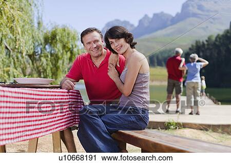 Stock Image - Couple sitting at picnic table together. Fotosearch
