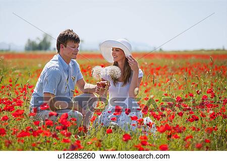 Couple sitting in field of poppies View Large Photo Image Stock Image - Couple sitting in field of poppies. Fotosearch