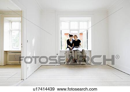 Stock Photo - Couple sitting in window of new home. Fotosearch