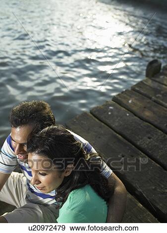 Couple sitting on dock together View Large Photo Image Stock Photo - Couple sitting on dock together. Fotosearch