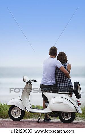 Couple sitting on scooter together View Large Photo Image Stock Photo - Couple sitting on scooter together. Fotosearch