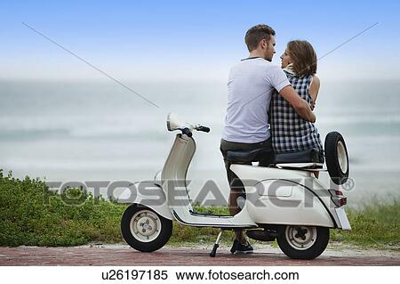 Couple sitting on scooter together View Large Photo Image Stock Photography - Couple sitting on scooter together. Fotosearch