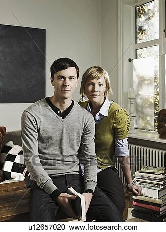Couple sitting together in living room View Large Photo Image Stock Image - Couple sitting together in living room. Fotosearch