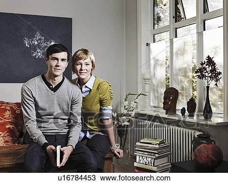 Couple sitting together in living room View Large Photo Image Stock Image - Couple sitting together in living room. Fotosearch