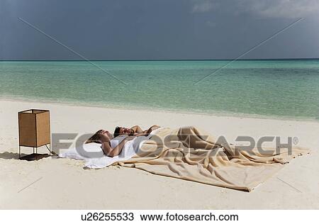 Stock Image - Couple sleeping in bed on beach. Fotosearch