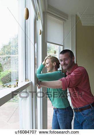 Couple standing by window together View Large Photo Image Stock Photo - Couple standing by window together. Fotosearch