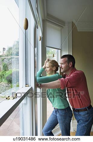 Couple standing by window together View Large Photo Image Stock Photograph - Couple standing by window together . Fotosearch