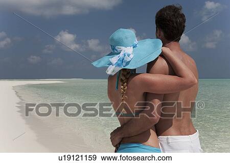 Stock Photo - Couple standing on tropical beach. Fotosearch
