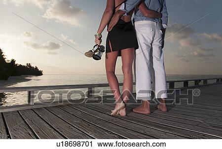 Stock Image - Couple standing together on dock. Fotosearch