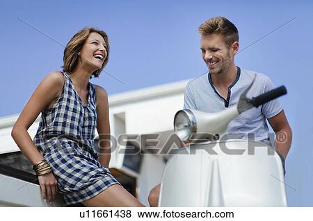 Couple talking by scooter View Large Photo Image Stock Photo - Couple talking by scooter. Fotosearch