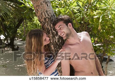 Stock Photo - Couple talking under tree on beach. Fotosearch