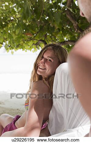 Stock Photography - Couple talking under tree on beach. Fotosearch