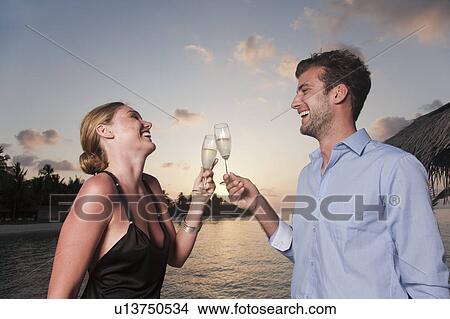 Picture - Couple toasting each other on dock. Fotosearch