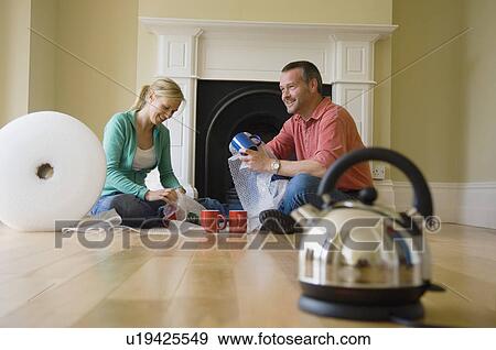 Stock Photo - Couple unpacking coffee cups in new home. Fotosearch