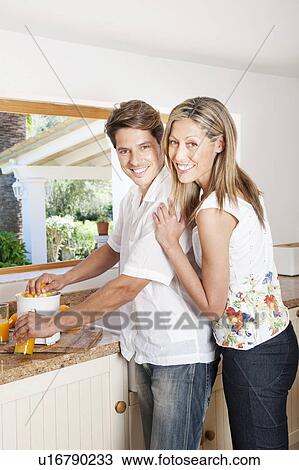 Stock Image - Couple using a juicer in kitchen. Fotosearch