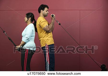 Couple using exercise machines in gym View Large Photo Image Stock Image - Couple using exercise machines in gym. Fotosearch