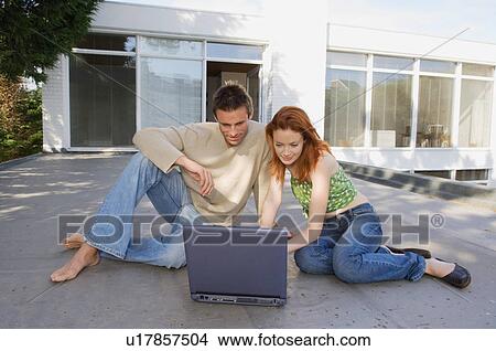 Couple using laptop together outdoors View Large Photo Image Picture - Couple using laptop together outdoors. Fotosearch