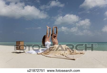 Stock Image - Couple waking up in bed on beach. Fotosearch