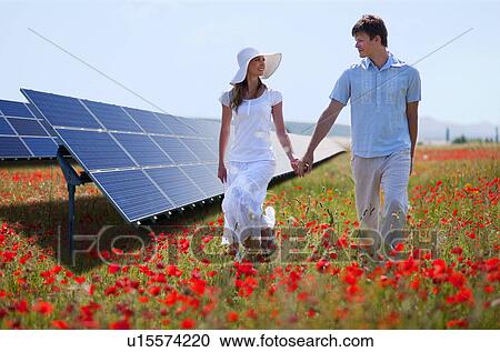 Stock Image - Couple walking by solar panels. Fotosearch