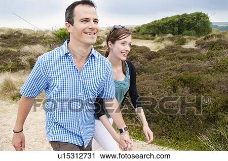 Couple walking hand-in-hand on beach View Large Photo Image Stock Image - Couple walking hand-in-hand on beach. Fotosearch
