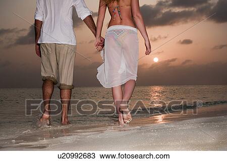 Couple walking hand-in-hand on beach View Large Photo Image Stock Image - Couple walking hand-in-hand on beach. Fotosearch