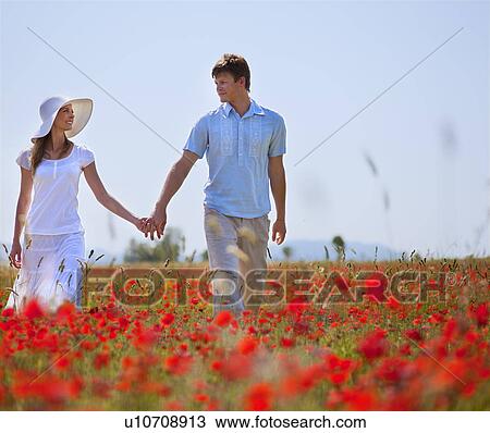 Couple walking in field of poppies View Large Photo Image Stock Image - Couple walking in field of poppies. Fotosearch