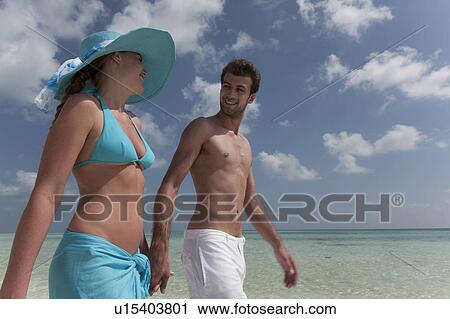 Stock Image - Couple walking on tropical beach. Fotosearch