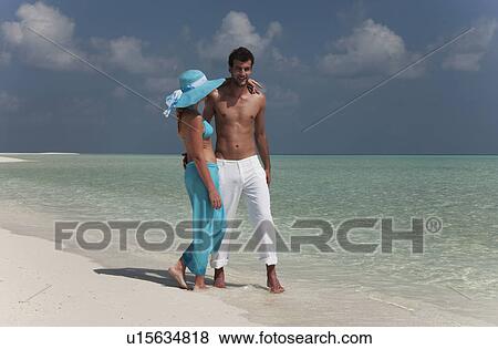 Stock Photo - Couple walking on tropical beach. Fotosearch