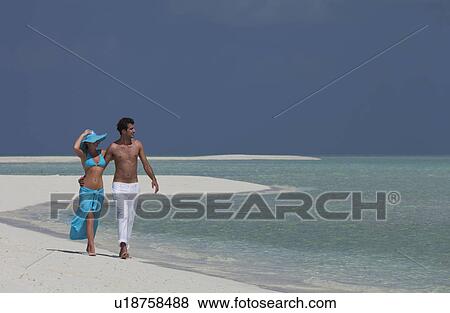 Stock Photo - Couple walking on tropical beach. Fotosearch