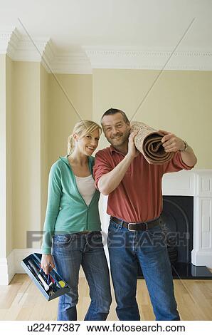 Stock Photo - Couple with rolled carpet in new home. Fotosearch